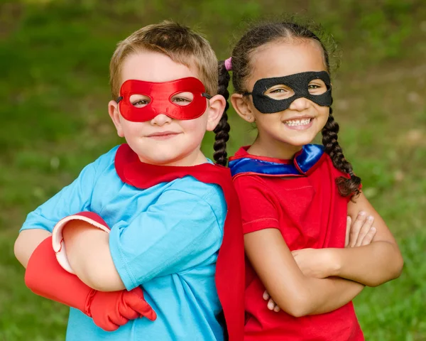 Pretty mixed race girl and Caucasian boy pretending to be superhero Stock Picture