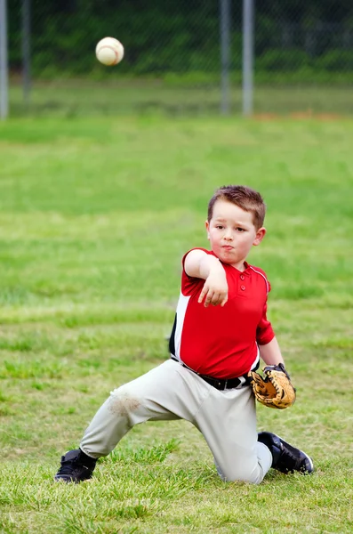 Kind in uniform gooien honkbal tijdens spel — Stockfoto