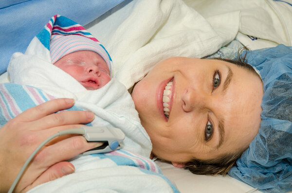 Mother hugs her new infant after delivering child by c-section