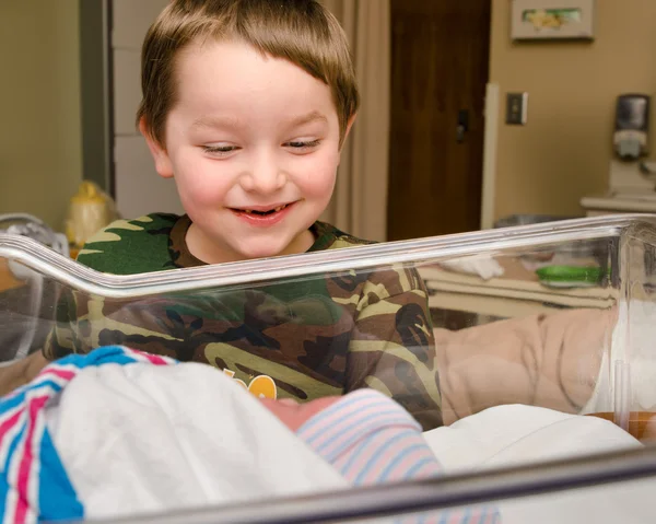 Взволнованный мальчик впервые встречает своего младшего брата после родов в больнице — стоковое фото
