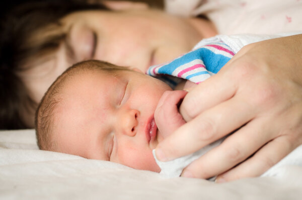 Newborn infant child resting next to mother after delivery at hospital