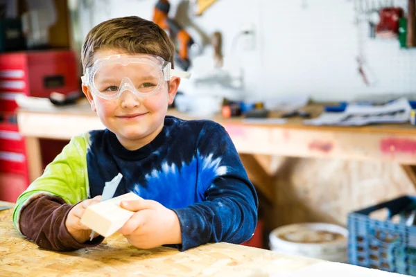 Parent dessine un pochoir sur un bloc de bois à utiliser comme corps pour une voiture Pinewood Derby — Photo