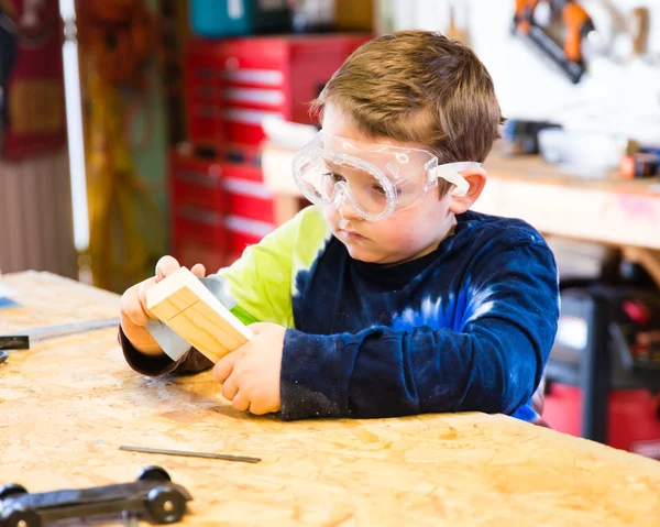 Parent draws stencil on wood block to be used as body for Pinewood Derby car — Stock Photo, Image