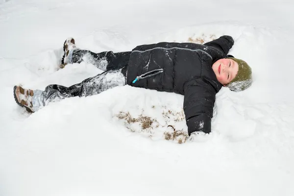 Ребенок играет в снег, делая снежного ангела — стоковое фото