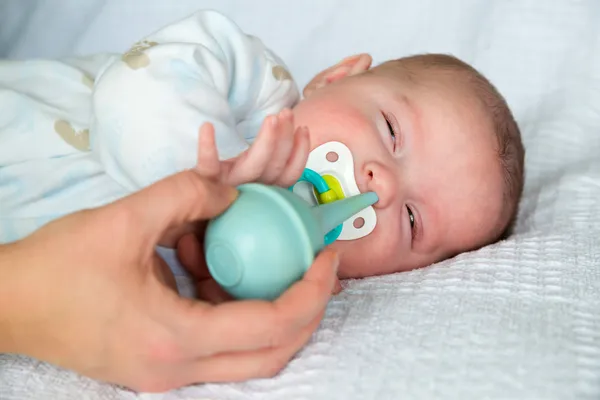 Mother using bulb syringe to clean unhappy infant baby's nose — Stock Photo, Image