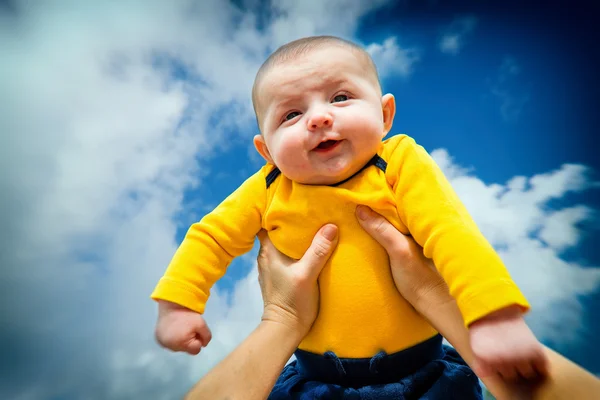 Счастливого улыбающегося ребенка поднимают в воздух — стоковое фото