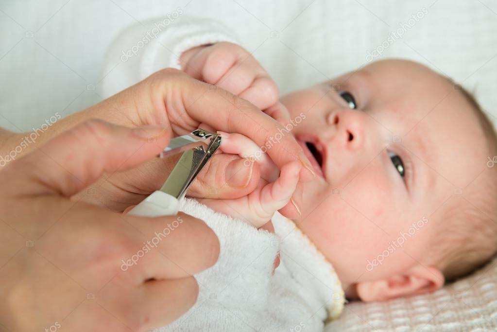 Mother cutting baby's fingernails with nail clippers Stock Photo by
