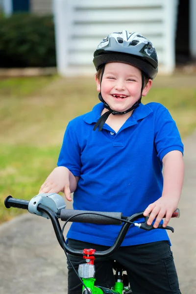 Счастливый ребенок катается на велосипеде возле своего дома — стоковое фото