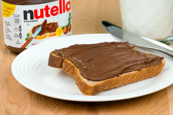 Kruik van nutella met toast en melk — Stockfoto