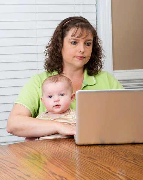 Mutter hält Baby während der Arbeit am Computer — Stockfoto