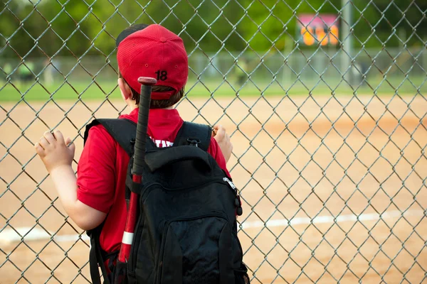 Jovem jogador de beisebol assistindo jogo de cerca externa — Fotografia de Stock