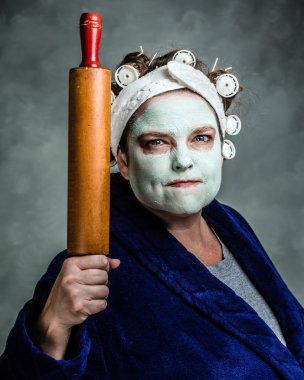 Mean and ugly housewife with facial mask, hair rollers and rolling pin clipart