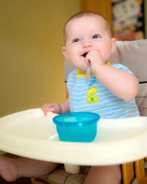 Bebê feliz menino comendo refeição enquanto sentado em cadeira alta — Fotografia de Stock