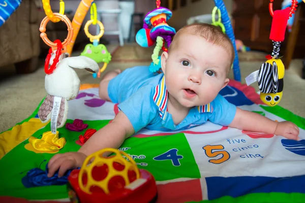 Gelukkig en nieuwsgierig baby babyjongen spelen op activiteit mat Stockafbeelding
