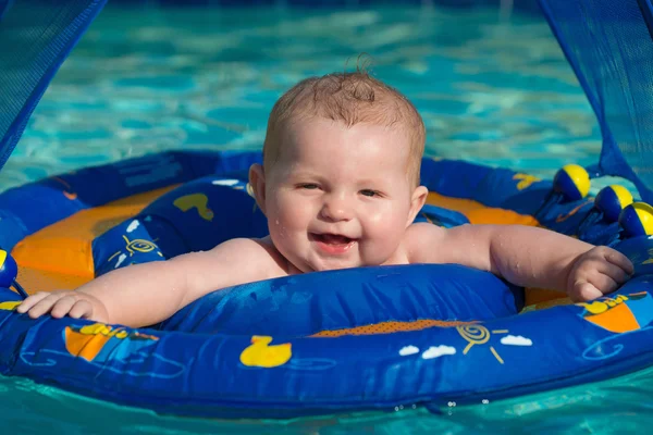 Happy infant playing in pool while sitting in baby float with canopy — Stock Photo, Image