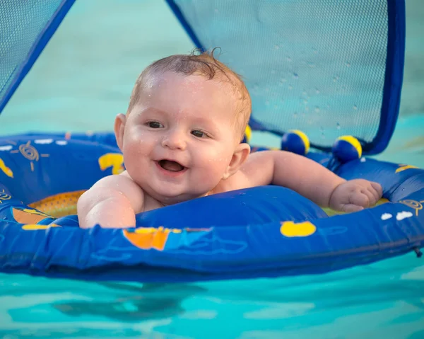 Happy infant playing in pool while sitting in baby float with canopy — Stock Photo, Image