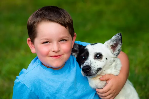 Criança amorosamente abraça seu cão de estimação — Fotografia de Stock