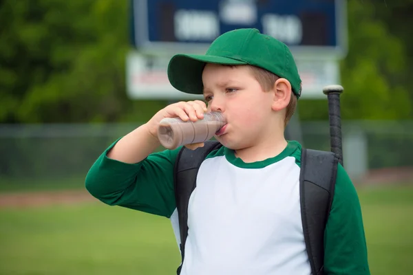 Gracz baseball dziecko pije mleko czekoladowe po grze — Zdjęcie stockowe