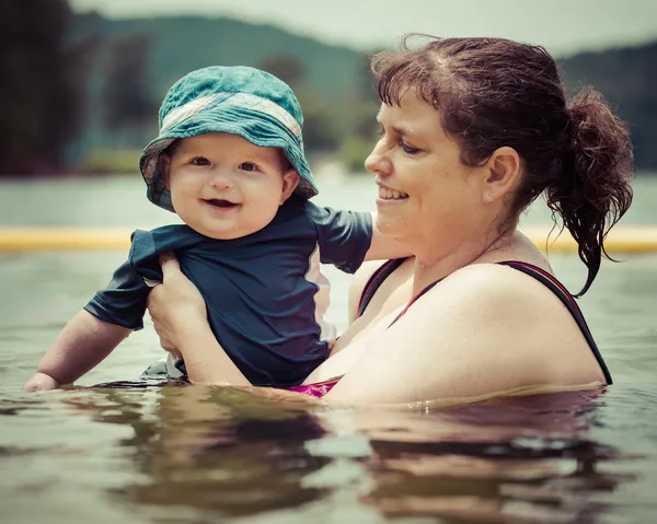 Mother teaching infant baby son to swim in lake during summer in — Stock Photo, Image