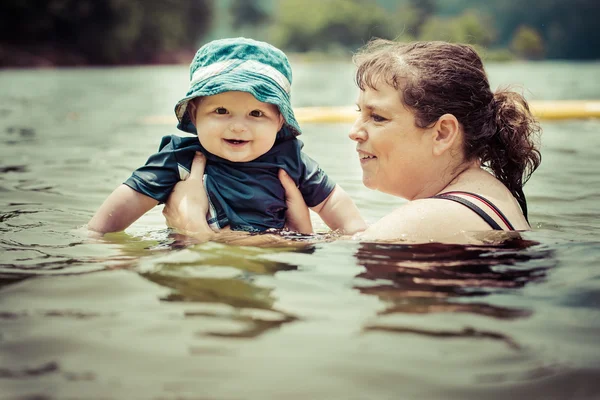 Mãe ensinando bebê bebê filho a nadar no lago durante o verão em — Fotografia de Stock