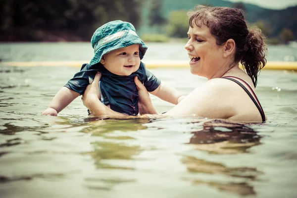 Mãe ensinando bebê bebê filho a nadar no lago durante o verão em — Fotografia de Stock