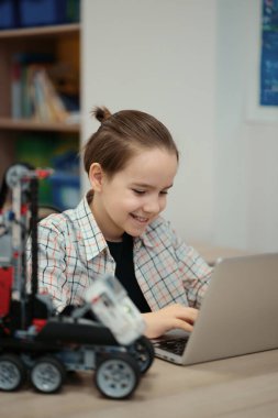 Çocuk tam fonksiyonel robot yapıyor ve bunu okul robotları için dizüstü bilgisayarla programlıyor.