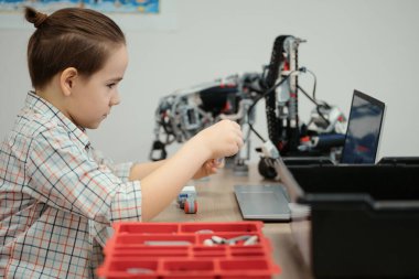 Çocuk tam fonksiyonel robot yapıyor ve bunu okul robotları için dizüstü bilgisayarla programlıyor.