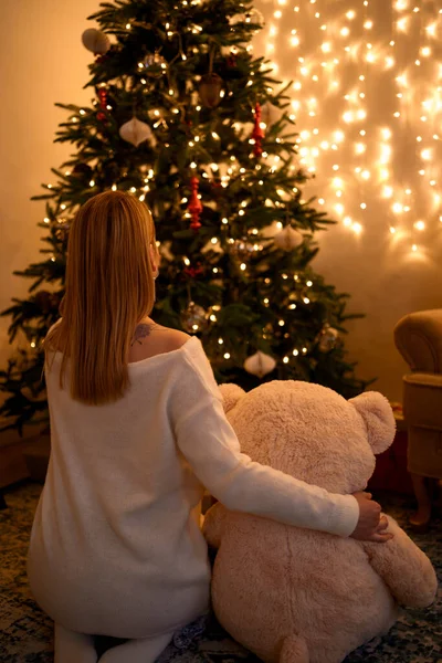 Frau umarmt Bären beim Blick auf Weihnachtsbaum — Stockfoto