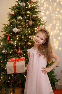 Tatillerde hediye kutusunu tutan küçük bir kız.