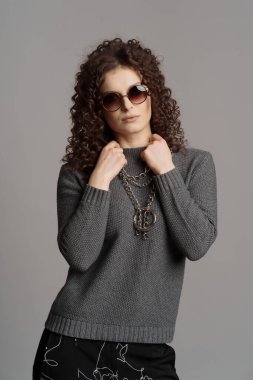 Gri arka planda güneş gözlüklü büyüleyici bir kız..