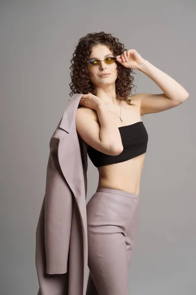 Mujer en cuero ropa elegante y gafas de sol verdes sobre fondo gris estudio —  Fotos de Stock