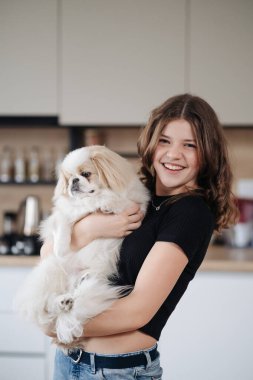 Genç bir kadın köpeğine sarılıyor.