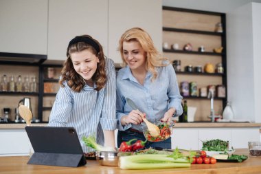 Anne ve kızı birlikte yemek pişiriyorlar.