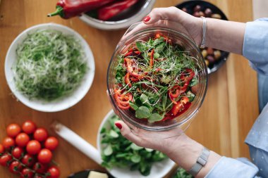 Kadın eli, sebze arkaplanda salata olan bir kase tutar.