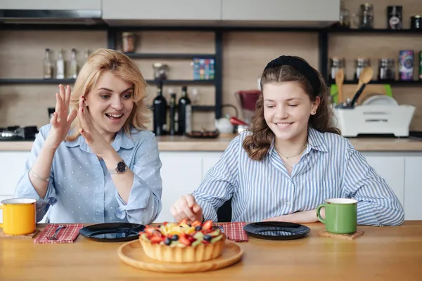 Madre e hija comiendo sabroso pastel de bayas con té en casa —  Fotos de Stock