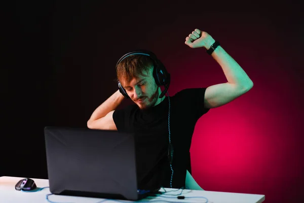 Gamer playing video games with headphones on neon light background