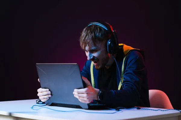Guy gamer vencedor com fone de ouvido jogando jogos de vídeo em seu computador pessoal — Fotografia de Stock