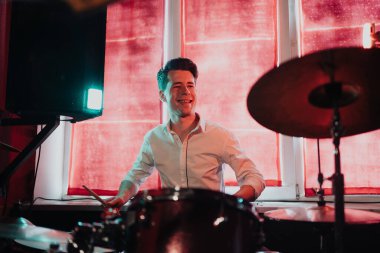 Yakışıklı adam konsere hazırlanırken davul çalıyor.