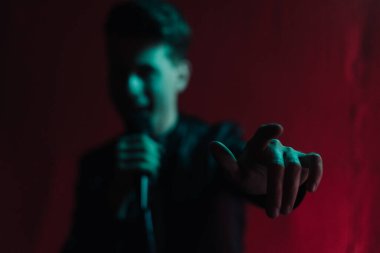 Deri ceketli bir adam kulüpte karanlık bir sahnede gösteri yapıyor.