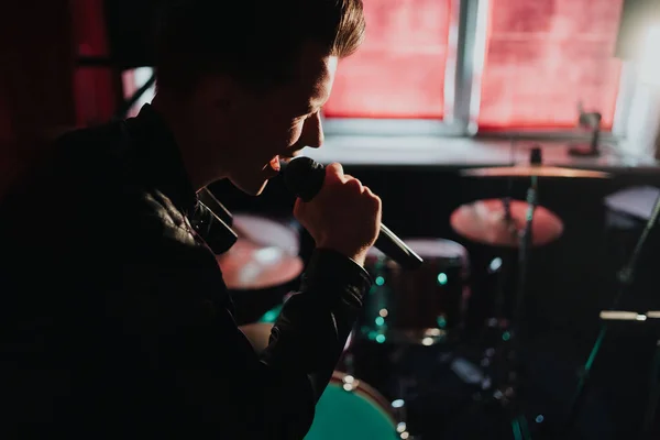 Deri ceketli bir adam otantik bir stüdyoda karanlık bir yerde şarkı söylüyor. — Stok fotoğraf