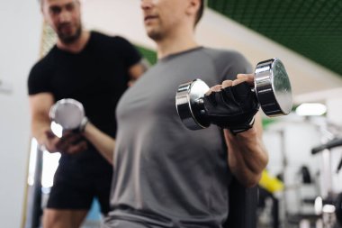 Genç adam spor salonunda kişisel antrenörle antrenman yapıyor.