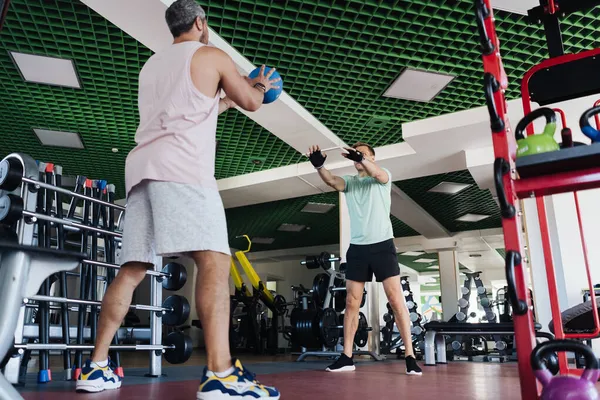 Jovem tem treino com personal trainer no ginásio — Fotografia de Stock