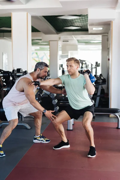 Jovem tem treino com personal trainer no ginásio — Fotografia de Stock