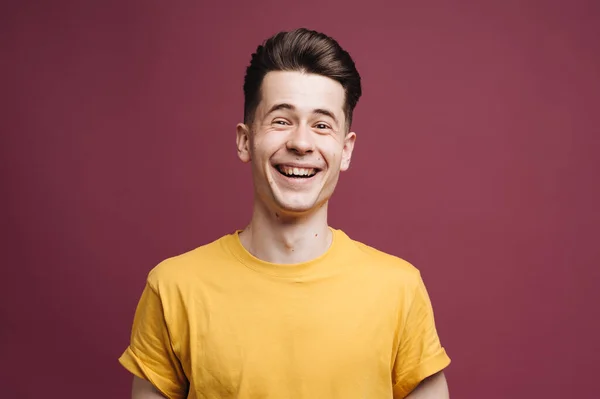 Közelkép portré mosolygós jóképű fickó barna pólóban elszigetelt bíbor háttér — Stock Fotó