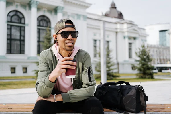 Jóképű férfi élvezi a zenét és a kávét egy napsütéses napon a parkban — Stock Fotó