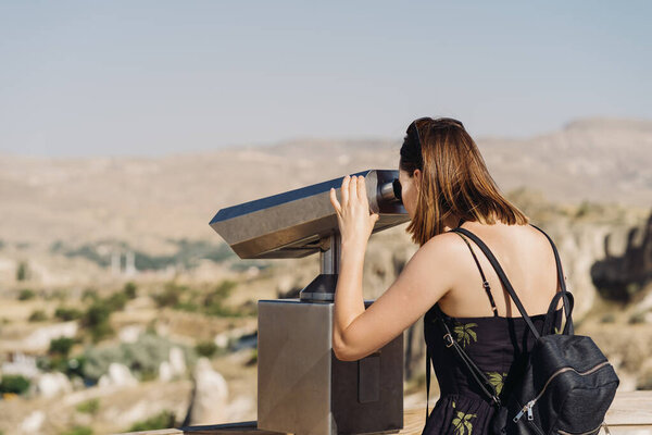 Young girl looking through a coin operated public binoculars in Turkey
