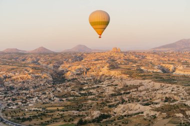 Türkiye 'nin Kapadokya kentindeki beyaz dağların tepesinde uçan sıcak hava balonu