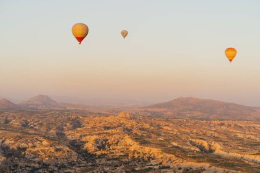 Türkiye 'nin Kapadokya kentindeki beyaz dağların tepesinde uçan sıcak hava balonu