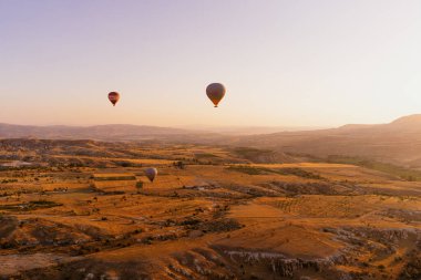 Türkiye 'nin Kapadokya kentindeki beyaz dağların tepesinde uçan sıcak hava balonu