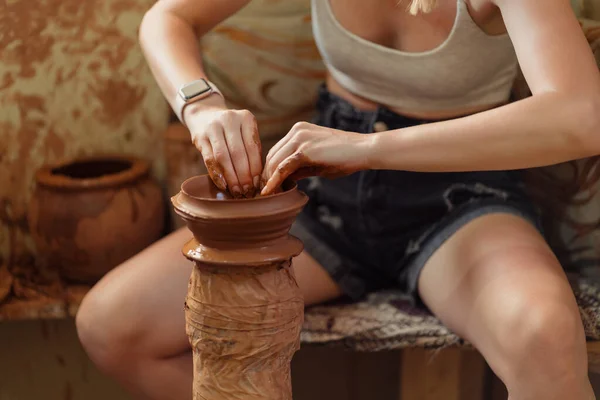 Close-up of unrecognizable woman with wet dirty hands shaping clay vase on pottery wheel. — Stock Photo, Image